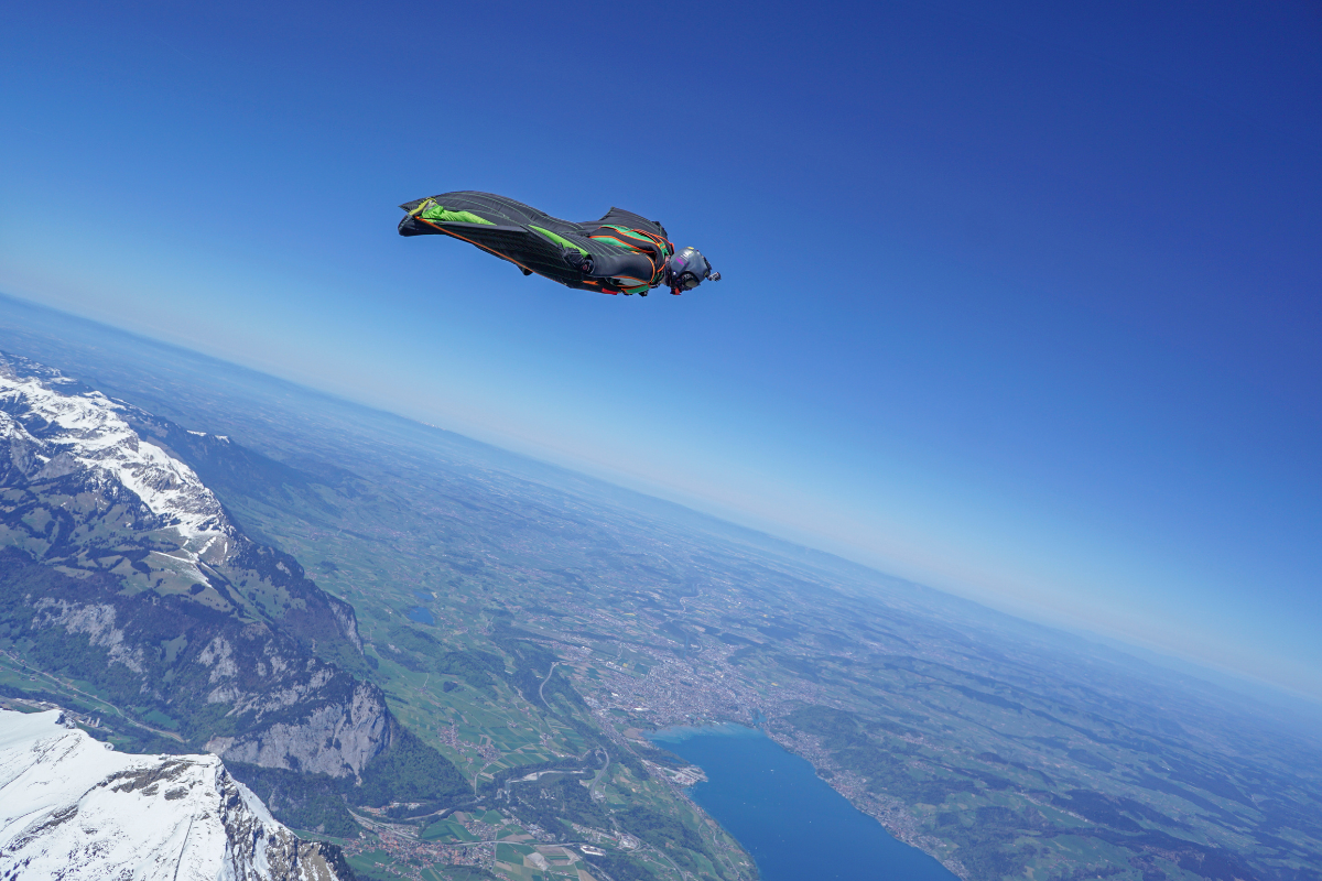 Person in a wingsuit, flying over the earth, blue sky